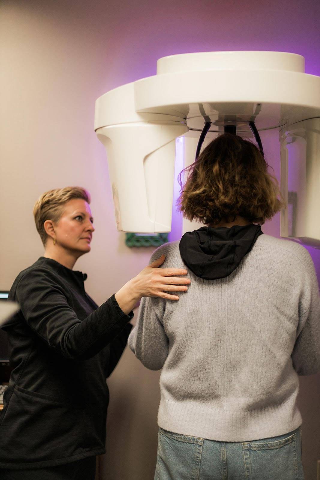 At Origin Dental Wellness, a holistic and health-centered dental practice located in Tulsa, Oklahoma, our skilled technician compassionately assists an individual with shoulder-length hair during a dental X-ray procedure. We prioritize comfort and precision in every aspect of care at this trusted Tulsa-based biological dentist office.